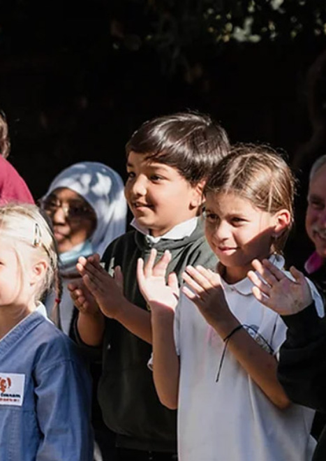 Enfants de l'école Cours Ozanam applaudissant lors d'un événement en plein air.